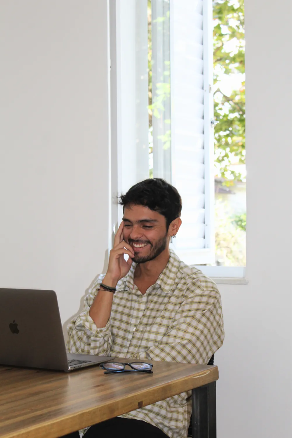 Sebastián Luque sonriendo en su escritorio, junto a una ventana