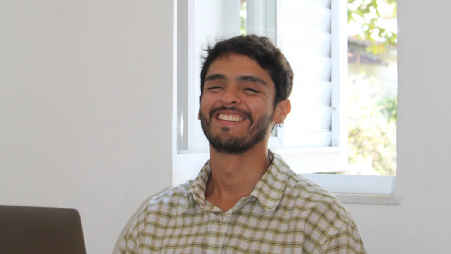 Sebastián sonriendo junto a una ventana luminosa